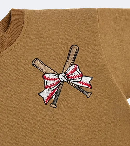Flat lay detail photography showing embroidered graphic artwork on a tan children's sweatshirt.