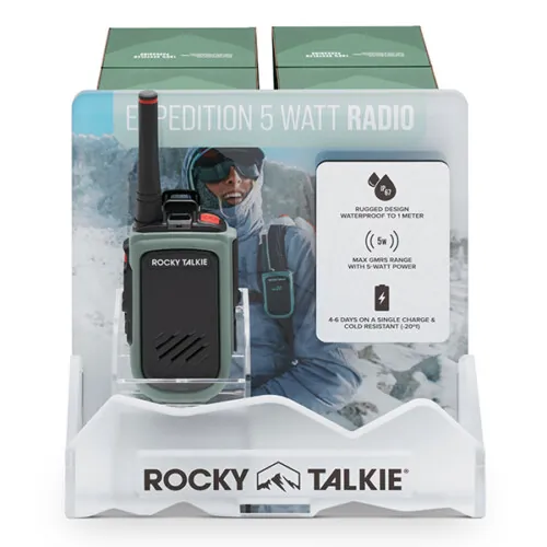 Olive green two-way radio on a branded retail display stand with winter expedition imagery, packaging product photography