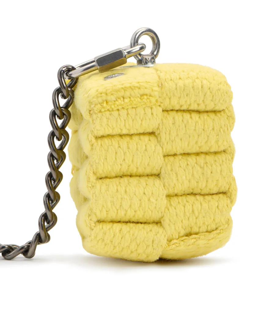 Close-up product photography of a single yellow woven charm on a silver chain