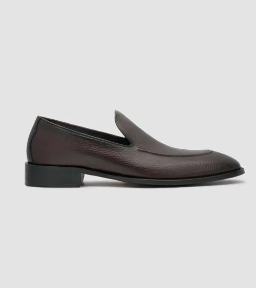 Single dark brown burnished leather penny loafer in side profile on grey background, footwear product photography
