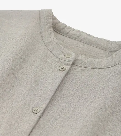Flat lay detail photography showing fabric texture and button construction on a beige cardigan for apparel product photography.