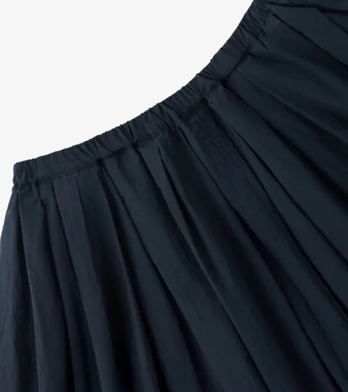 Flat lay detail photography showing gathered waistband construction on black wide-leg pants.