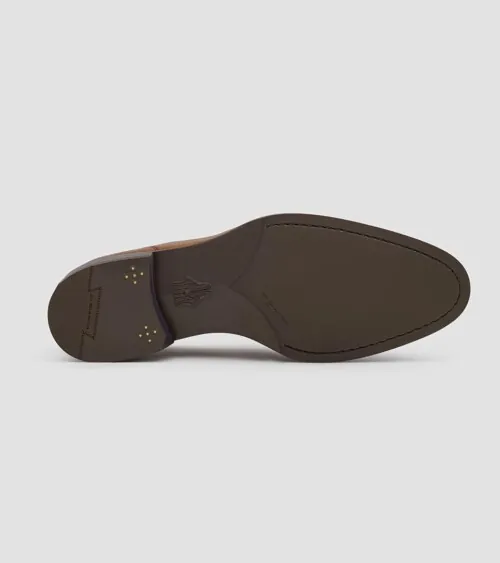 Single loafer showing the brown leather sole, on grey background, detail product photography