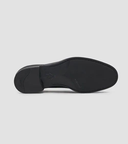 Single black leather loafer showing the smooth leather sole, on grey background, detail product photography