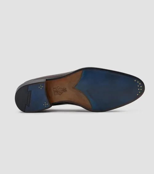 Single loafer showing a blue and brown leather sole, on grey background, detail product photography