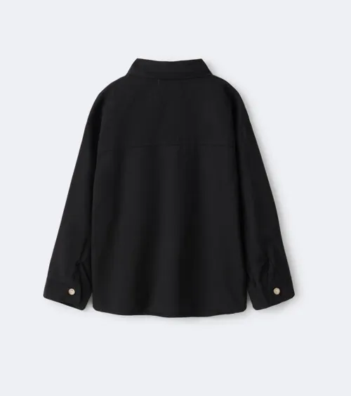 Flat lay photography showing the back view of a black children's button-down shirt for online retail clothing photography.