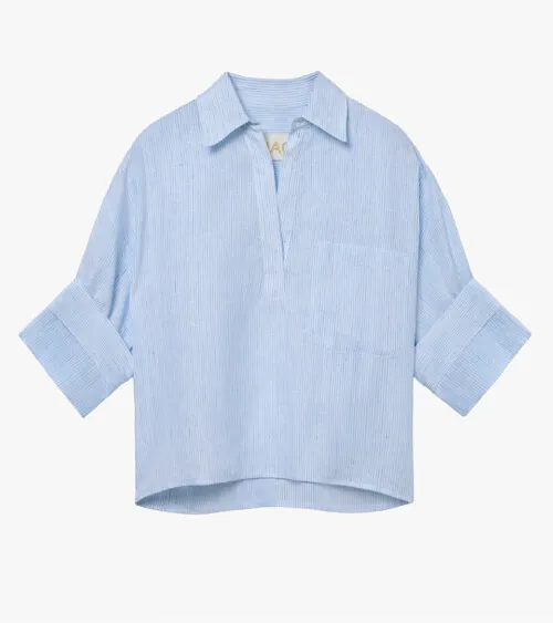 Flat lay photography of a light blue women's blouse with rolled sleeves for online retail clothing photography.