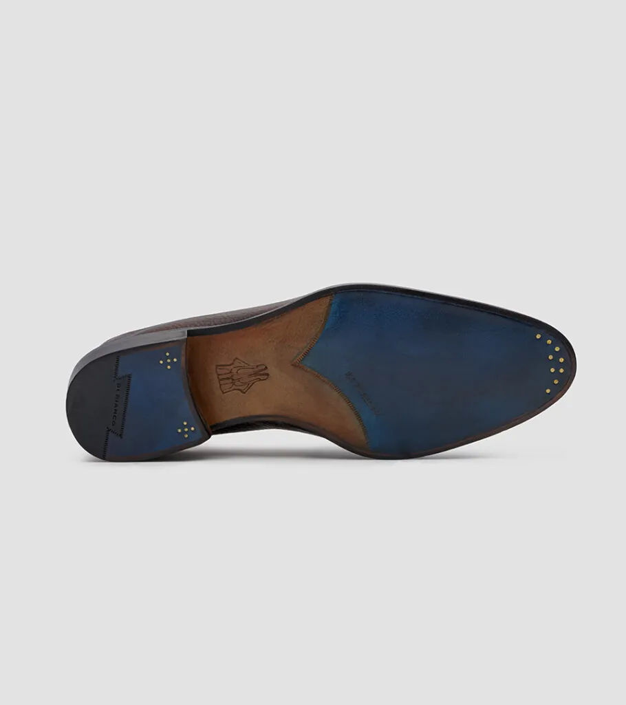Shoe product photography of a black leather loafer tipped on its side to show the leather sole and heel