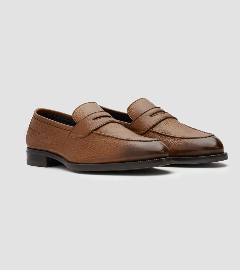 Shoe product photography of a two-tone tan and dark brown penny loafer in side profile