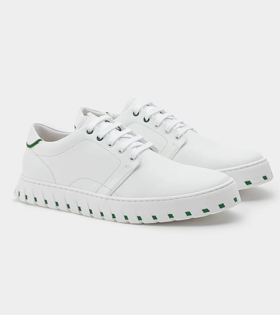 Shoe product photography of a white leather lace-up sneaker at a front three-quarter angle with a ridged white sole