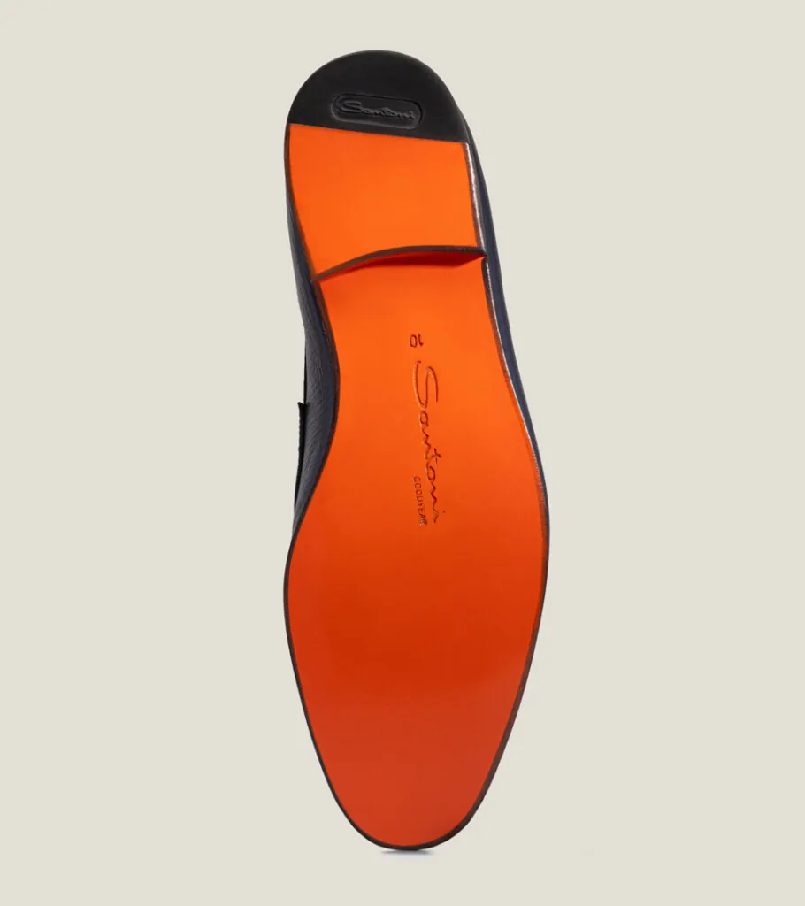 Shoe product photography of a navy leather loafer turned to show the full orange leather sole