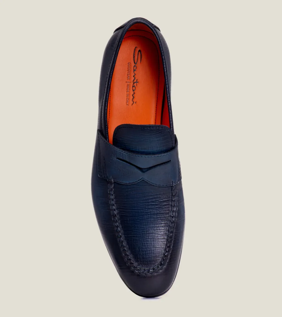 Shoe product photography of a navy leather penny loafer shot from directly overhead showing the orange lining