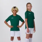 Two youth models in matching dark green soccer jerseys and white shorts