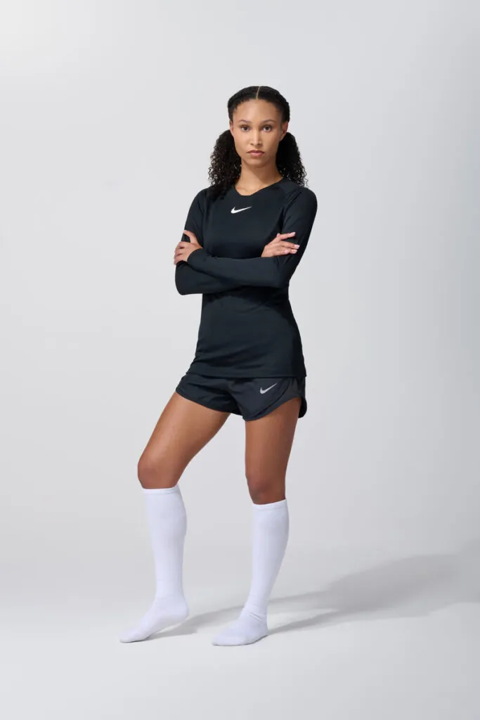 Female model in black long sleeve adidas top with white shorts and socks