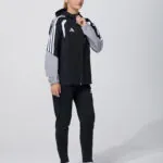Female model in black and grey adidas track jacket and pants