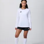 Female model in white long sleeve soccer jersey and white shorts