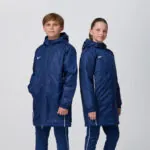 Two youth models in matching navy Nike puffer jackets and pants
