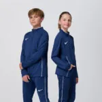 Two youth models in matching navy Nike track jackets and pants