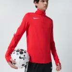 Male model in red Nike long sleeve jacket holding a soccer ball