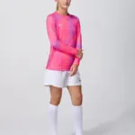 Female model in pink long sleeve soccer jersey and white shorts