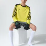 Male model in yellow goalkeeper kit, seated
