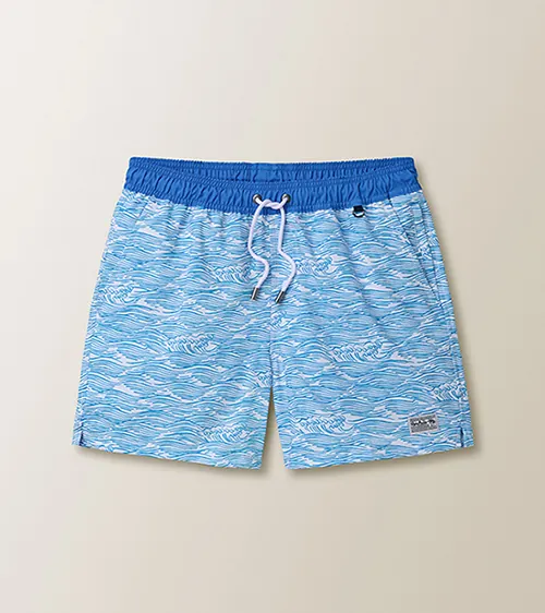 Flat lay product photography of light blue wave-print men’s swim trunks