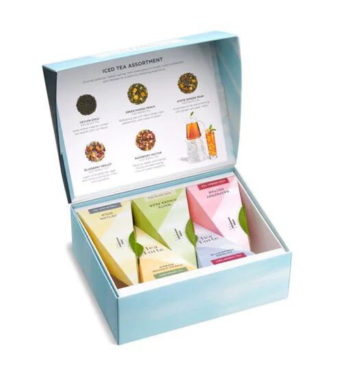 eCommerce product photography of a Tea Forte gift collection with assorted tea blends in premium packaging for a luxury tea brand website.