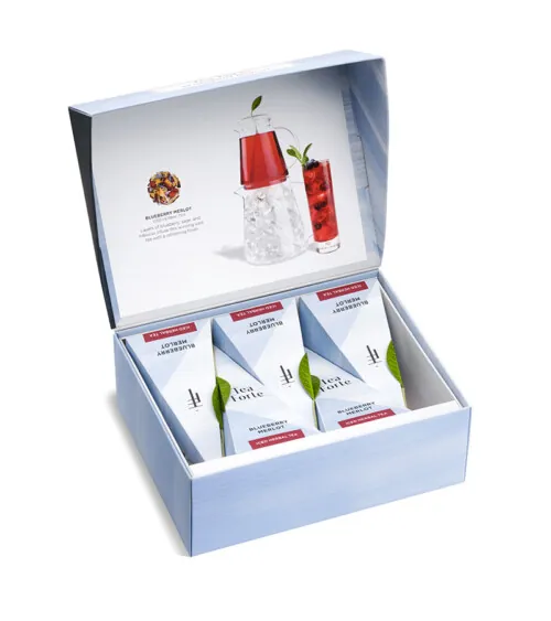 Luxury product photography of a Tea Forte gift box with assorted tea pyramids and tea bottle on a white background for an eCommerce product listing.